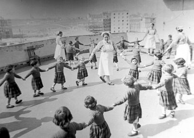 Niños y niñas en una de las terrazas de la prisión de madres lactantes de Ventas, con las presas cuidadoras. 15/3/1955. Fondo Santos Yubero. ARCM. Sig. 1.067.